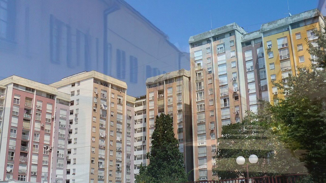 Stambena ulica u Zagrebu, blago sunce, održavano zelenilo i parkirani automobili